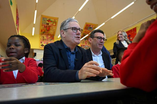 Britain's Prime Minister Keir Starmer (2nd L) meets school children at a breakfast club with Manchester Mayor Andy Burnham (back R), during a visit to a primary school in Ashton-under-Lyne, Greater Manchester, north-west England on April 13, 2026. (Photo by Paul ELLIS / POOL / AFP)