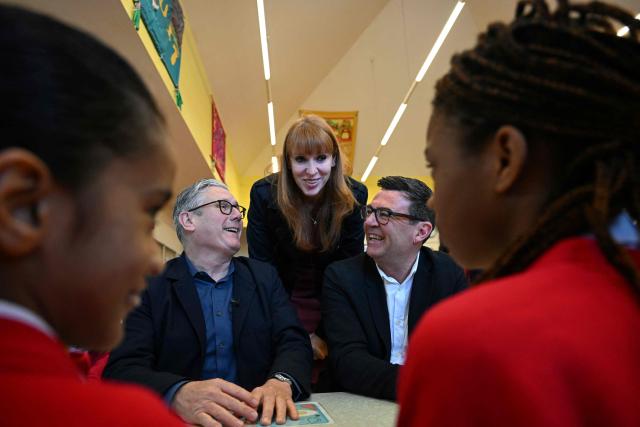 Britain's Prime Minister Keir Starmer (L), Labour Party MP and former deputy prime minister, Angela Rayner (C) and Manchester Mayor Andy Burnham (R) meet with schoolchildren during a visit to a primary school in Ashton-under-Lyne, Greater Manchester, north-west England on April 13, 2026. (Photo by Paul ELLIS / POOL / AFP)