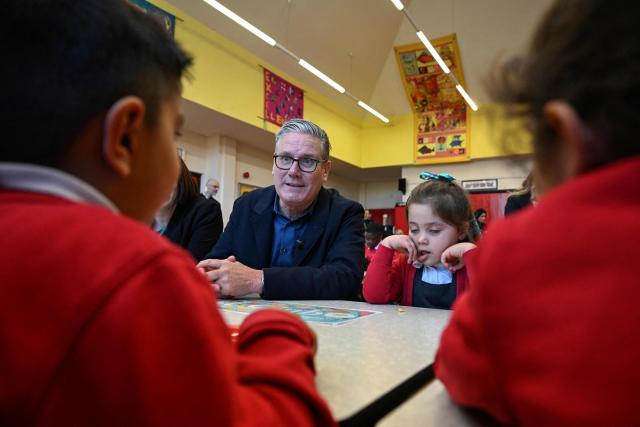 Britain's Prime Minister Keir Starmer (C) meets school children at a breakfast club with Manchester Mayor Andy Burnham, during a visit to a primary school in Ashton-under-Lyne, Greater Manchester, north-west England on April 13, 2026. (Photo by Paul ELLIS / POOL / AFP)