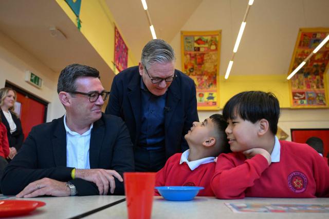 Britain's Prime Minister Keir Starmer (centre L) meets school children at a breakfast club with Manchester Mayor Andy Burnham (L), during a visit to a primary school in Ashton-under-Lyne, Greater Manchester, north-west England on April 13, 2026. (Photo by Paul ELLIS / POOL / AFP)