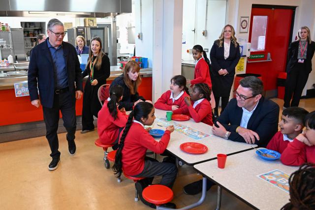 Britain's Prime Minister Keir Starmer (L) meets school children at a breakfast club with Manchester Mayor Andy Burnham (R), during a visit to a primary school in Ashton-under-Lyne, Greater Manchester, north-west England on April 13, 2026. (Photo by Paul ELLIS / POOL / AFP)