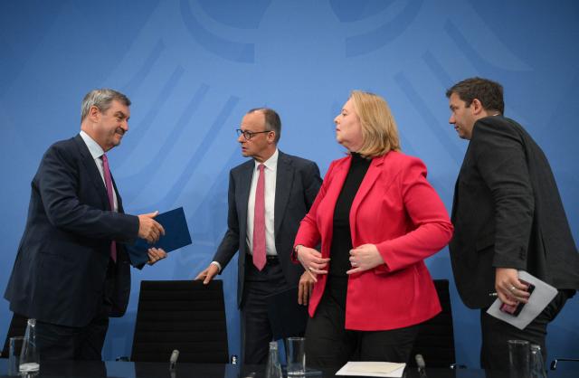 (L-R) Bavaria's State Premier and leader of the conservative Christian Social Union (CSU) Markus Soeder, German Chancellor Friedrich Merz, German Minister for Labour and Social Affairs Baerbel Bas (SPD) and German Finance Minister and Vice Chancellor Lars Klingbeil (SPD) stand up at the end of a press briefing on the results of their overnight coalition committee consultations, on April 13, 2026 at the Chancellery in Berlin. Chancellor Friedrich Merz said that Germany would cut petrol and diesel taxes for two months to provide relief to households and businesses hit by the energy shock during the Middle East war. (Photo by RALF HIRSCHBERGER / AFP)