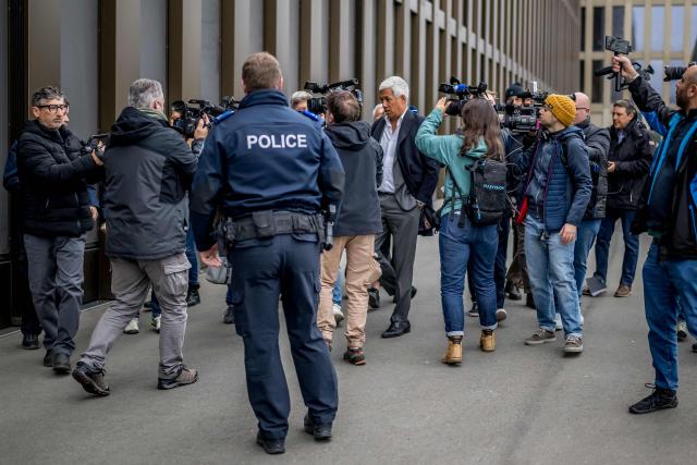 Bar owners Jacques et Jessica Moretti's lawyer Nicola Meier (C) is surrounded by journalists upon his arrival to the hearing of the Mayor of Crans-Montana Nicolas Feraud as part of the investigation over the fire that broke out in the bar "Le Constellation" during New Year celebrations, claiming 41 lives, most of whom were teenagers, and injuring 115 more, in Sion, western Switzerland, on April 13, 2026. (Photo by Fabrice COFFRINI / AFP)