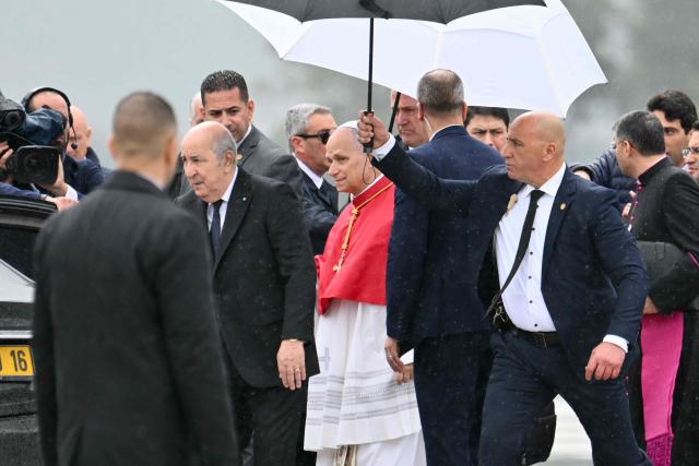 Pope Leo XIV is welcomed by Algeria's President Abdelmadjid Tebboune after landing at the Houari Boumediene International Airport on April 13, 2026. Pope Leo XIV embarks today on an 11-day visit to Algeria, Cameroon, Angola and Equatorial Guinea for his first major international trip since becoming pontiff last year. (Photo by Alberto PIZZOLI / AFP)