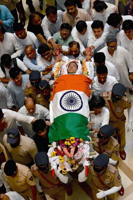 Mouners carry the body of late Bollywood playback singer Asha Bhosle, shrouded in India's national flag during her funeral procession in Mumbai on April 13, 2026. Legendary Indian playback singer Bhosle, whose voice defined Bollywood music through the 1970s and 80s, died on April 12 in Mumbai aged 92, her family said. (Photo by Sujit JAISWAL / AFP)