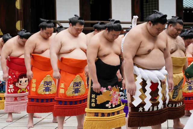 Top ranking sumo wrestlers bow as they take part in a traditional Shinto ceremony at Yasukuni Shrine in Tokyo on April 13, 2026, during the annual "honozumo", a ceremonial one-day exhibition for spectators held within the shrine's precincts. (Photo by Kazuhiro NOGI / AFP)