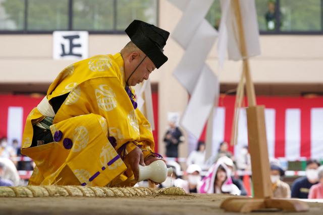 A sumo referee purifies the sumo ring before the annual "honozumo", a ceremonial one-day sumo exhibition for spectators held at Yasukuni Shrine in Tokyo on April 13, 2026. (Photo by Kazuhiro NOGI / AFP)