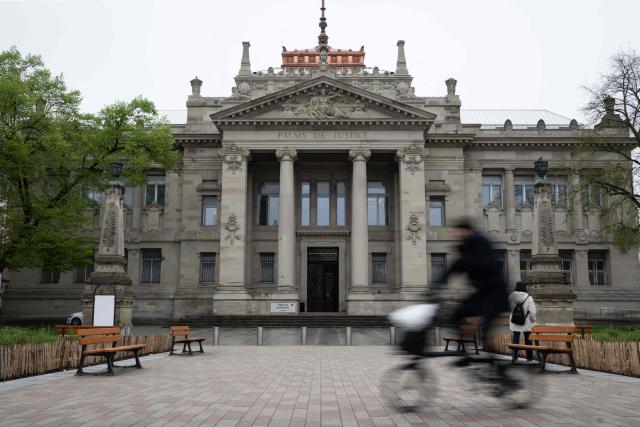 A cyclist rides a bike past the Strasbourg courthouse on April 13, 2026. (Photo by SEBASTIEN BOZON / AFP)