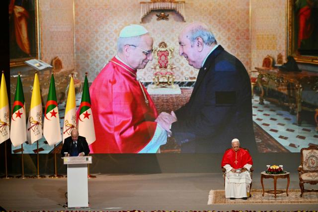 Pope Leo XIV listens to Algeria's President Abdelmadjid Tebboune during a meeting with the civil society and the diplomatic corps at the “Djamaa el Djazair” Conference Center  on April 13, 2026. Pope Leo XIV embarks today on an 11-day visit to Algeria, Cameroon, Angola and Equatorial Guinea for his first major international trip since becoming pontiff last year. (Photo by Alberto PIZZOLI / AFP)