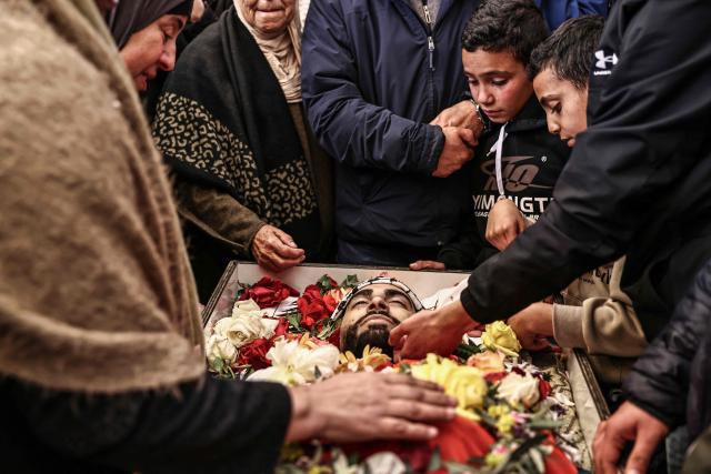 EDITORS NOTE: Graphic content / TOPSHOT - Relatives of 23-year-old Ali Majed Hamadneh bid him farewell during his funeral in the village of Deir Jarir, northeast of the city of Ramallah in the Israeli-occupied Palestinian West Bank on April 13, 2026. The Palestinian health ministry reported on April 12, 2026, that Israeli settlers shot dead Hamadneh in the occupied West Bank, while the military said a soldier had opened fire during a "violent riot". Violence in the West Bank, which Israel has occupied since 1967, has risen sharply since the October 7, 2023 Hamas attack on Israel triggered the Gaza war. (Photo by Zain JAAFAR / AFP)