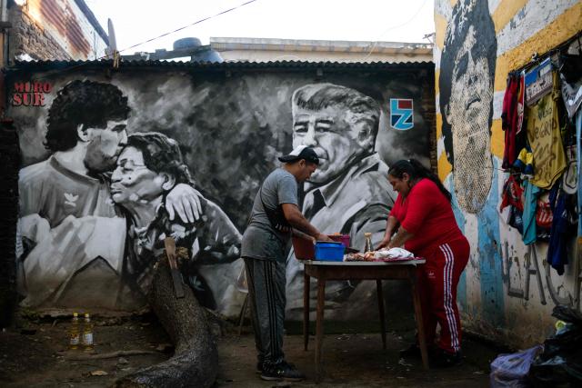 Cook Maria Torres and Alejandro, a volunteer, prepare a stew for neighbours in need at the yard of the childhood home of the late football star Diego Maradona, now transformed into a soup kitchen, in Villa Fiorito, Buenos Aires province, Argentina, on April 9, 2026. The second trial over the death of football star Diego Maradona begins on April 14, 2026, after the first one, which took place last year, was annulled when it was discovered that one of the judges was taking part in a clandestine documentary about the proceedings. (Photo by TOMAS CUESTA / AFP)
