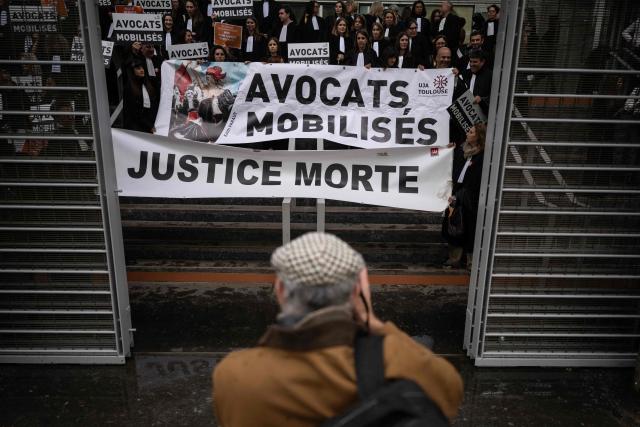 A placard reading "Lawyers mobilised. Dead justice" is seen as lawyers gather on the steps of Toulouse's courthouse to protest Justice Minister Gerald Darmanin's draft bill, in particular his proposal to introduce plea bargaining in criminal matters, in Toulouse on April 13, 2026. (Photo by Lionel BONAVENTURE / AFP)