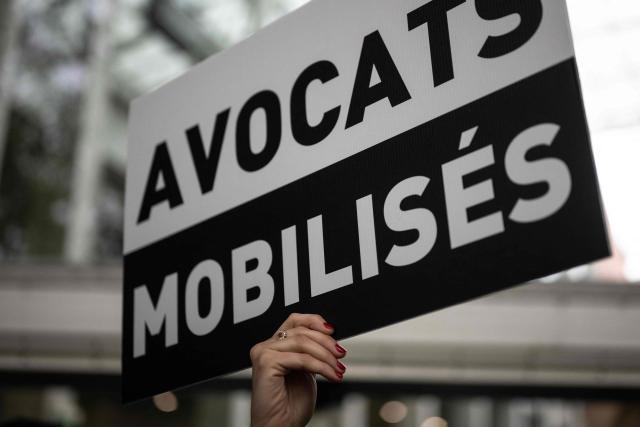 A placard reading "Lawyers mobilised" is seen as lawyers gather on the steps of Toulouse's courthouse to protest Justice Minister Gerald Darmanin's draft bill, in particular his proposal to introduce plea bargaining in criminal matters, in Toulouse on April 13, 2026. (Photo by Lionel BONAVENTURE / AFP)