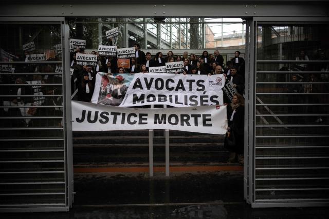 A placard reading "Lawyers mobilised. Dead justice" is seen as lawyers gather on the steps of Toulouse's courthouse to protest Justice Minister Gerald Darmanin's draft bill, in particular his proposal to introduce plea bargaining in criminal matters, in Toulouse on April 13, 2026. (Photo by Lionel BONAVENTURE / AFP)