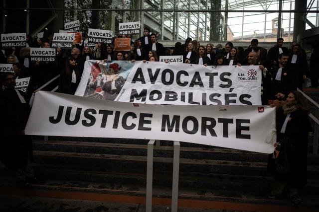 A placard reading "Lawyers mobilised. Dead justice" is seen as lawyers gather on the steps of Toulouse's courthouse to protest Justice Minister Gerald Darmanin's draft bill, in particular his proposal to introduce plea bargaining in criminal matters, in Toulouse on April 13, 2026. (Photo by Lionel BONAVENTURE / AFP)