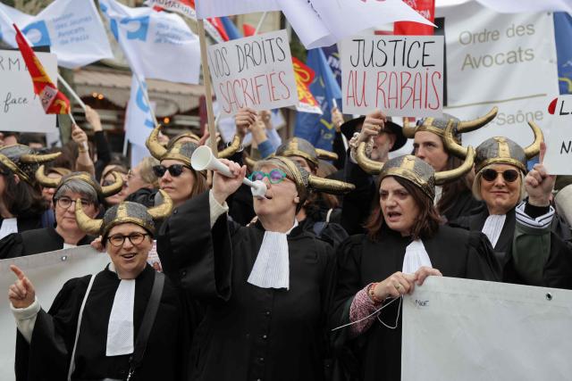Lawyers hold placards reading "Your rights sacrificed" and "Justice on the cheap" as they take part in a demonstration against the "SURE" (Useful, Fast and Effective Sentencing) draft bill, in particular its proposal to introduce plea bargaining in criminal matters, as the French Senate begins debating the text, in Paris on April 13, 2026. Lawyers across France staged a nationwide "Justice morte" (Dead Justice) stoppage called by most of the country's 164 bar associations, as the Senate opened debate on the bill which the government says is needed to tackle a backlog of more than 6,000 pending criminal cases. (Photo by Ludovic MARIN / AFP)