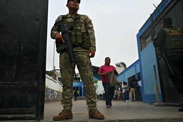 A member of the Armed Forces and a policeman stand guard at a polling station in Lima on April 13, 2026, after logistical failures prevented tens of thousands of people from voting in presidential and legislative elections the day before. Peru's Keiko Fujimori looked set to face a runoff against a conservative rival after a troubled first-round presidential election on April 12, 2026 marred by logistics foul-ups, police raids and allegations of fraud. (Photo by ERNESTO BENAVIDES / AFP)