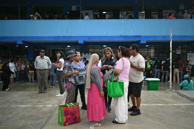 An employee of the National Office of Electoral Processes (ONPE) hels people find their polling tables at a school in Lima on April 13, 2026, after logistical failures prevented tens of thousands of people from voting in presidential and legislative elections the day before. Peru's Keiko Fujimori looked set to face a runoff against a conservative rival after a troubled first-round presidential election on April 12, 2026 marred by logistics foul-ups, police raids and allegations of fraud. (Photo by ERNESTO BENAVIDES / AFP)