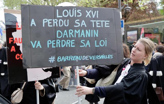 A lawyer holds placard reading "Louis XVI lost his head, Darmanin will lose his law - Versailles Bar Association" during a demonstration against the "SURE" (Useful, Fast and Effective Sentencing) draft bill, in particular its proposal to introduce plea bargaining in criminal matters, as the French Senate begins debating the text, in Paris on April 13, 2026. Lawyers across France staged a nationwide "Justice morte" (Dead Justice) stoppage called by most of the country's 164 bar associations, as the Senate opened debate on the bill which the government says is needed to tackle a backlog of more than 6,000 pending criminal cases. (Photo by Ludovic MARIN / AFP)