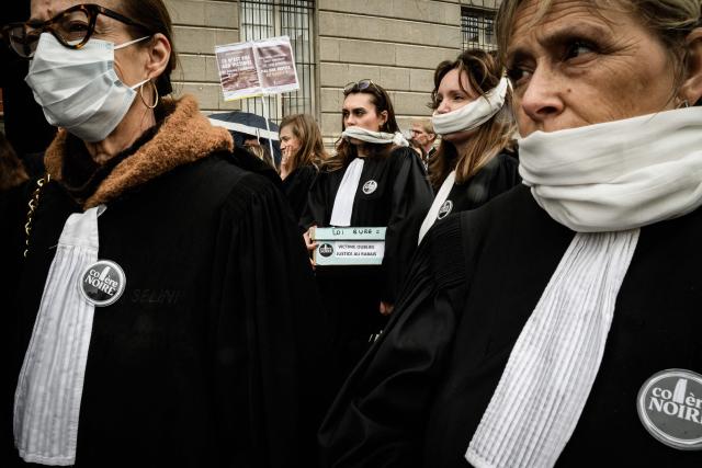 Lawyers gather with their mouths taped shut, in front of the Chambery courthouse, during a demonstration by lawyers against the "SURE" (Useful, Fast and Effective Sentencing) draft bill, in particular its proposal to introduce plea bargaining in criminal matters, as the French Senate begins debating the text, in Chambery on April 13, 2026. Lawyers across France staged a nationwide "Justice morte" (Dead Justice) stoppage called by most of the country's 164 bar associations, as the Senate opened debate on the bill which the government says is needed to tackle a backlog of more than 6,000 pending criminal cases. (Photo by JEFF PACHOUD / AFP)