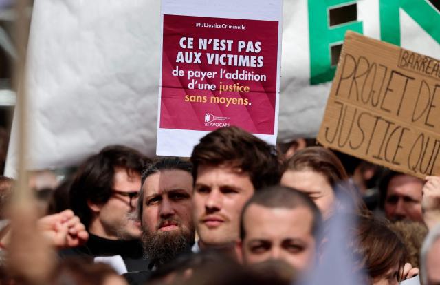 A protester holds placard reading "It is not the victims who should foot the bill for a judicial system that lacks resources" during a demonstration against the "SURE" (Useful, Fast and Effective Sentencing) draft bill, in particular its proposal to introduce plea bargaining in criminal matters, as the French Senate begins debating the text, in Paris on April 13, 2026. Lawyers across France staged a nationwide "Justice morte" (Dead Justice) stoppage called by most of the country's 164 bar associations, as the Senate opened debate on the bill which the government says is needed to tackle a backlog of more than 6,000 pending criminal cases. (Photo by Ludovic MARIN / AFP)