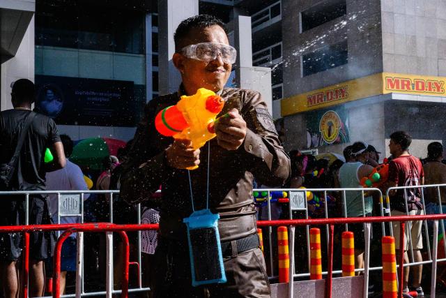 A police officer smiles as he takes part in mass water fights with revellers on the first day of Songkran, or Thai New Year, in Bangkok on April 13, 2026. (Photo by Anthony WALLACE / AFP)