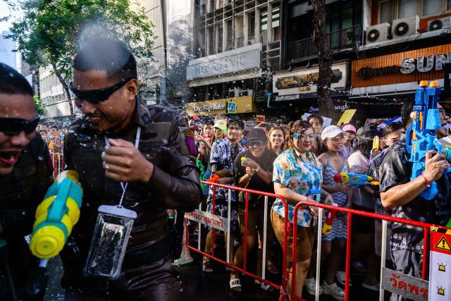 Police (L) are sprayed by revellers taking part in mass water fights on the first day of Songkran, or Thai New Year, in Bangkok on April 13, 2026. (Photo by Anthony WALLACE / AFP)