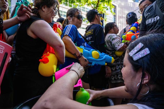 A woman helps revellers refill their water guns as they take part in mass water fights on the first day of Songkran, or Thai New Year, in Bangkok on April 13, 2026. (Photo by Anthony WALLACE / AFP)