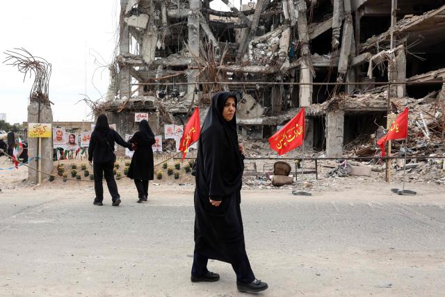 Iranians walk past portraits of victims reportedly killed in a US-Israeli airstrike on the residential building near which they are displayed, in Tehran on April 13, 2026. The US military said it would begin a blockade of all Iranian ports on April 13, after talks between the warring sides in Pakistan collapsed with the US president blaming the Islamic republic's refusal to abandon its nuclear ambitions. (Photo by AFP) / 