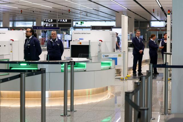 Airport personnel stand at the security check area of the new Terminal 1 pier during its official opening at Munich International Airport in Munich, southern Germany on April 13, 2026. The Terminal 1 Pier provides additional capacity for up to six million passengers per year. The new building is currently one of Bavaria’s largest infrastructure projects. (Photo by ALEXANDRA BEIER / AFP)