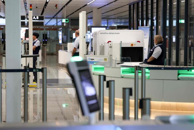 Airport personnel stand at the security check area of the new Terminal 1 pier during its official opening at Munich International Airport in Munich, southern Germany on April 13, 2026. The Terminal 1 Pier provides additional capacity for up to six million passengers per year. The new building is currently one of Bavaria’s largest infrastructure projects. (Photo by ALEXANDRA BEIER / AFP)