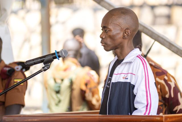 Christopher Okello Onyum, suspected in the killing of four toddlers at a daycare in Ggaba, stands in the dock during his trial at the Ggaba Community Church Grounds in Kampala on April 13, 2026. A man has admitted stabbing four young children to death at a kindergarten in Uganda, saying he believed killing them as human sacrifices would make him wealthy, prosecutors said April 8, 2026.
The public trial of the defendant, Christopher Okello Onyum, who holds both Ugandan and American citizenship, started on April 13, 2026. (Photo by Stuart Tibaweswa / AFP)