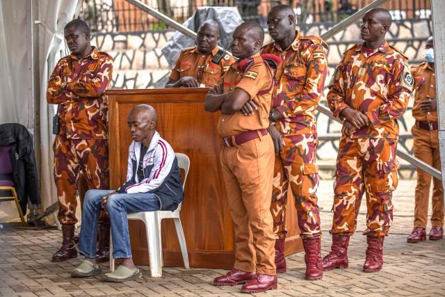 Christopher Okello Onyum (2nd L), suspected in the killing of four toddlers at a daycare in Ggaba, attends his trial at the Ggaba Community Church Grounds in Kampala on April 13, 2026. A man has admitted stabbing four young children to death at a kindergarten in Uganda, saying he believed killing them as human sacrifices would make him wealthy, prosecutors said April 8, 2026.
The public trial of the defendant, Christopher Okello Onyum, who holds both Ugandan and American citizenship, started on April 13, 2026. (Photo by Stuart Tibaweswa / AFP)