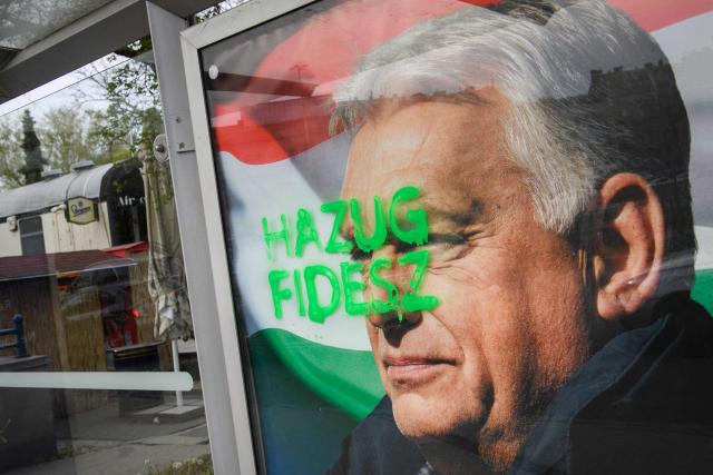 A tag reads 'Liar Fidesz' over a placard about a national petition against war, showing outgoing Hungarian Prime Minister and Fidesz leader Viktor Orban, at a bus stop near the South Railway Station in Budapest, Hungary on April 13, 2026, one day after general elections. Hungarian prime minister-elect Peter Magyar pledged on April 13 to usher in a "new era" after defeating nationalist leader Viktor Orban in elections seen as a blow to hard-right populism. (Photo by Ferenc ISZA / AFP)