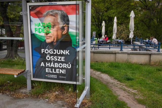 A tag reads 'Liar Fidesz' over a placard about a national petition against war, showing outgoing Hungarian Prime Minister and Fidesz leader Viktor Orban, at a bus stop near the South Railway Station in Budapest, Hungary on April 13, 2026, one day after general elections. Hungarian prime minister-elect Peter Magyar pledged on April 13 to usher in a "new era" after defeating nationalist leader Viktor Orban in elections seen as a blow to hard-right populism. (Photo by Ferenc ISZA / AFP)