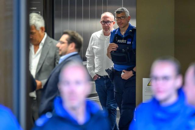 Mayor of Crans-Montana Nicolas Feraud (C) reacts as he is escorted by a police officer during a break of his hearing as part of the investigation over the fire that broke out in the bar "Le Constellation" during New Year celebrations, claiming 41 lives, most of them teenagers, and injuring 115 others, in Sion, western Switzerland, on April 13, 2026. (Photo by Fabrice COFFRINI / AFP)