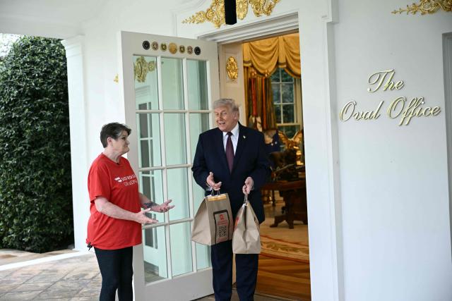 US President Donald Trump speaks a Doordash delivery worker after she delivered McDonald's at the Oval Office at the White House in Washington, DC, on April 13, 2026. (Photo by Brendan SMIALOWSKI / AFP)