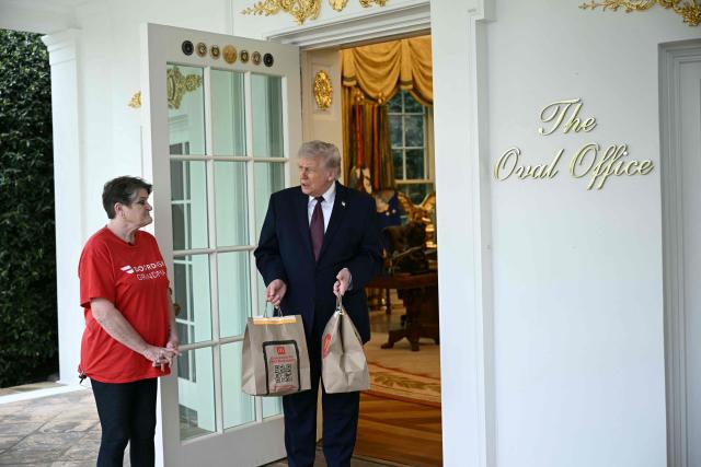 US President Donald Trump speaks a Doordash delivery worker after she delivered McDonald's at the Oval Office at the White House in Washington, DC, on April 13, 2026. (Photo by Brendan SMIALOWSKI / AFP)