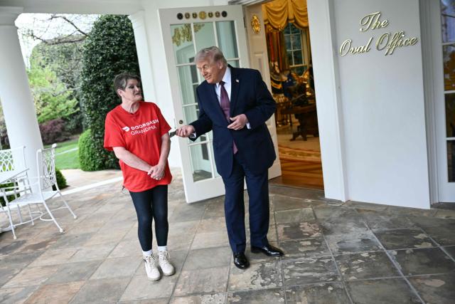 US President Donald Trump tips Doordash delivery worker Sharon Simmons after she delivered Mcdonald's outside of the Oval Office at the White House, in Washington, DC, April 13, 2026. (Photo by Brendan SMIALOWSKI / AFP)