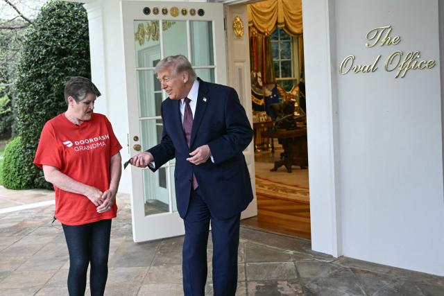 US President Donald Trump tips Doordash delivery worker Sharon Simmons after she delivered Mcdonald's outside of the Oval Office at the White House, in Washington, DC, April 13, 2026. (Photo by Brendan SMIALOWSKI / AFP)