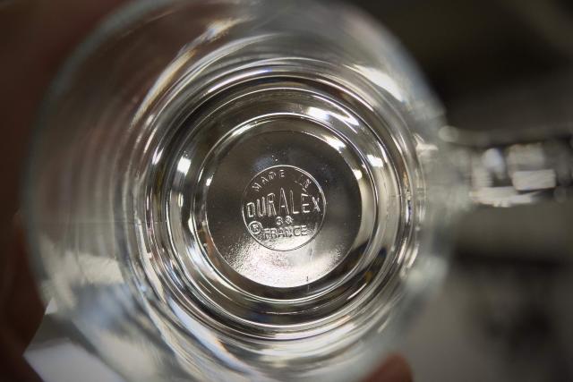 (FILES) A worker controls a glass at the end of a production line at the factory of French manufacturer of glassware Duralex in La Chapelle-Saint-Mesmin near Orleans, centre France, on July 31, 2024. Duralex, the globally known glassmaker recently taken over as a cooperative by its employees, announced on April 13, 2026 the replacement of its chief executive. Officially presented as preparation for his retirement, the departure may in fact be linked to economic difficulties facing the company. (Photo by GUILLAUME SOUVANT / AFP)
