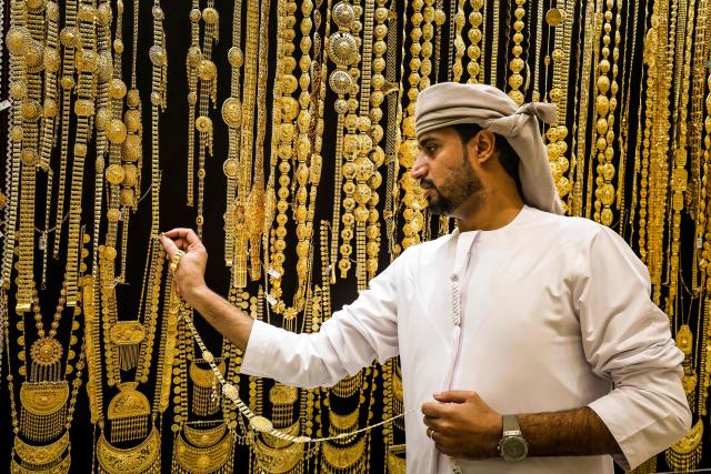 An Emirati gold dealer arranges a golden necklace in a jewelry shop in the Dubai Gold Souk on April 13, 2025. (Photo by FADEL SENNA / AFP)