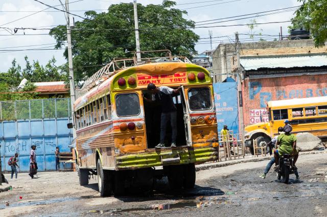 A man stands by the rear door of a bus used for public transportation in downtown Port-au-Prince, Haiti, on April 13, 2026. (Photo by Clarens SIFFROY / AFP)