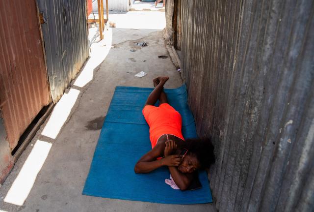 A woman uses a mobile phone while resting at a shelter for displaced people at the Rex Theatre in downtown Port-au-Prince, Haiti, on April 13, 2026. (Photo by Clarens SIFFROY / AFP)