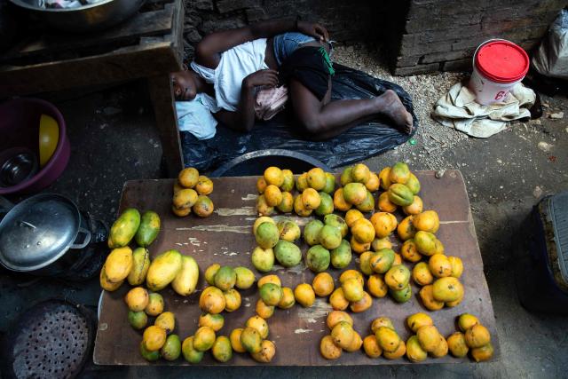 A woman rests while selling mangoes at a shelter for displaced people at the Rex Theatre in downtown Port-au-Prince, Haiti, on April 13, 2026. (Photo by Clarens SIFFROY / AFP)