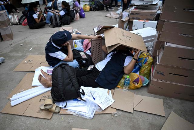 Election officials of Peru's National Office of Electoral Processes (ONPE) lie down on the floor as they inspect electoral materials for registration and storage during the second day of the presidential election in Pucallpa, Peru on April 13, 2026. Two Peruvian right-wing candidates looked set on April 13, 2026, to advance to a presidential runoff, after an election marred by logistical foul-ups and deep voter anger. Voting is still underway at around a dozen polling places in Lima, where ballot materials failed to arrive on time for April 12 election. (Photo by Hugo Alejos / AFP)