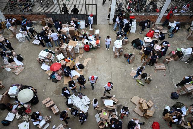Election officials of Peru's National Office of Electoral Processes (ONPE) inspect electoral materials for registration and storage during the second day of the presidential election in Pucallpa, Peru on April 13, 2026. Two Peruvian right-wing candidates looked set on April 13, 2026, to advance to a presidential runoff, after an election marred by logistical foul-ups and deep voter anger. Voting is still underway at around a dozen polling places in Lima, where ballot materials failed to arrive on time for April 12 election. (Photo by Hugo Alejos / AFP)