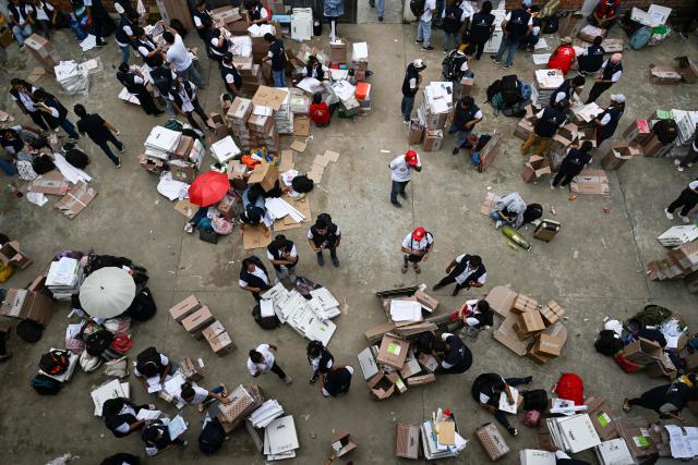 Election officials of Peru's National Office of Electoral Processes (ONPE) inspect electoral materials for registration and storage during the second day of the presidential election in Pucallpa, Peru on April 13, 2026. Two Peruvian right-wing candidates looked set on April 13, 2026, to advance to a presidential runoff, after an election marred by logistical foul-ups and deep voter anger. Voting is still underway at around a dozen polling places in Lima, where ballot materials failed to arrive on time for April 12 election. (Photo by Hugo Alejos / AFP)
