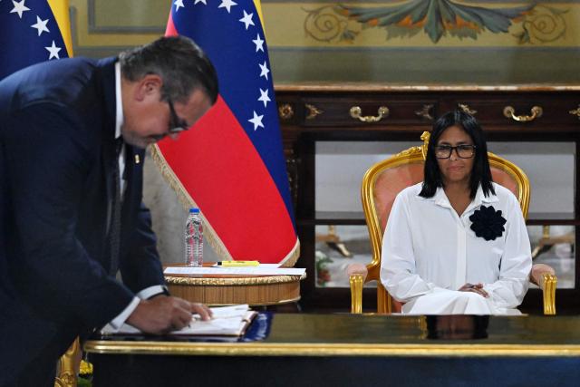 Venezuela's interim President Delcy Rodriguez, looks at the President of Chevron Venezuela, Mariano Vela, signing the document during a signing of an agreement ceremony between Chevron Venezuela and the national government at the Miraflores Palace in Caracas on April 13, 2026. (Photo by Juan BARRETO / AFP)
