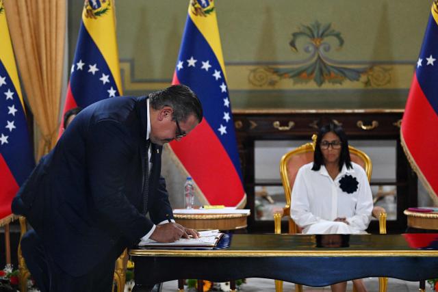 The President of Chevron Venezuela, Mariano Vela, signs the document next to Venezuela's interim President Delcy Rodriguez, during a signing of an agreement ceremony between Chevron Venezuela and the national government at the Miraflores Palace in Caracas on April 13, 2026. (Photo by Juan BARRETO / AFP)